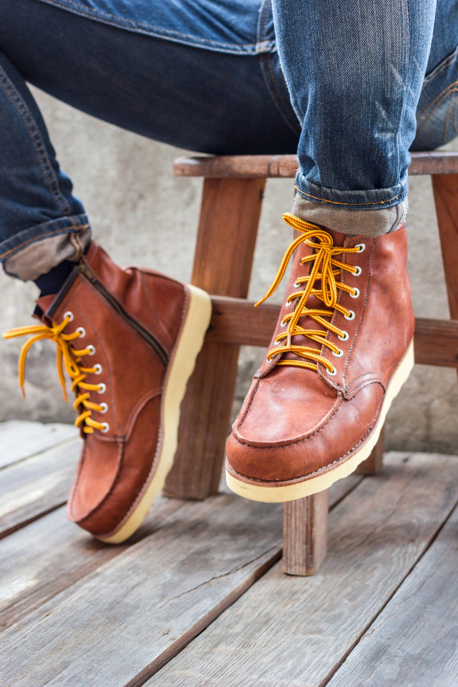 A pair of brown leather boots with laces placed on wooden floor,